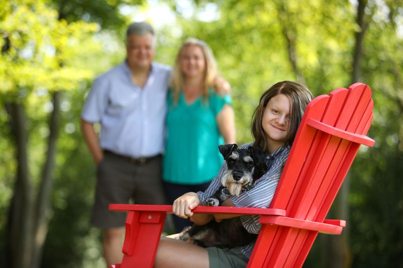 Sophia Pseno, 13, is photographed with her dog, Eggsy, and her parents, Steve and Carol, outside their Inverness home on Aug. 5, 2020. To help with Sophia's learning over the summer, the family has been reading and baking together. (Stacey Wescott / Chicago Tribune)